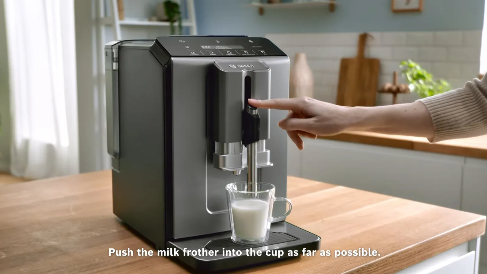A Bosch coffee machine with a milk frother making coffee on a wooden counter.