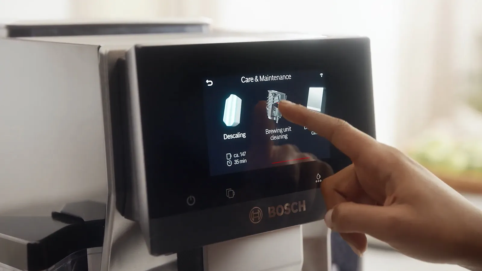 Person uses Bosch coffee machine's touchscreen for care and maintenance options.