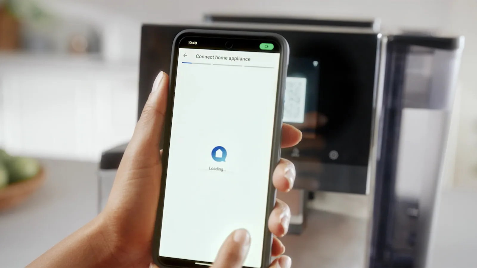 Hand holding a smartphone connecting to a Bosch coffee machine via an app interface.