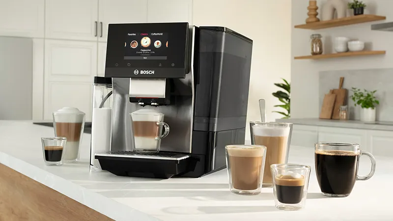 Bosch coffee machine on a counter with various coffee drinks and a modern kitchen background.