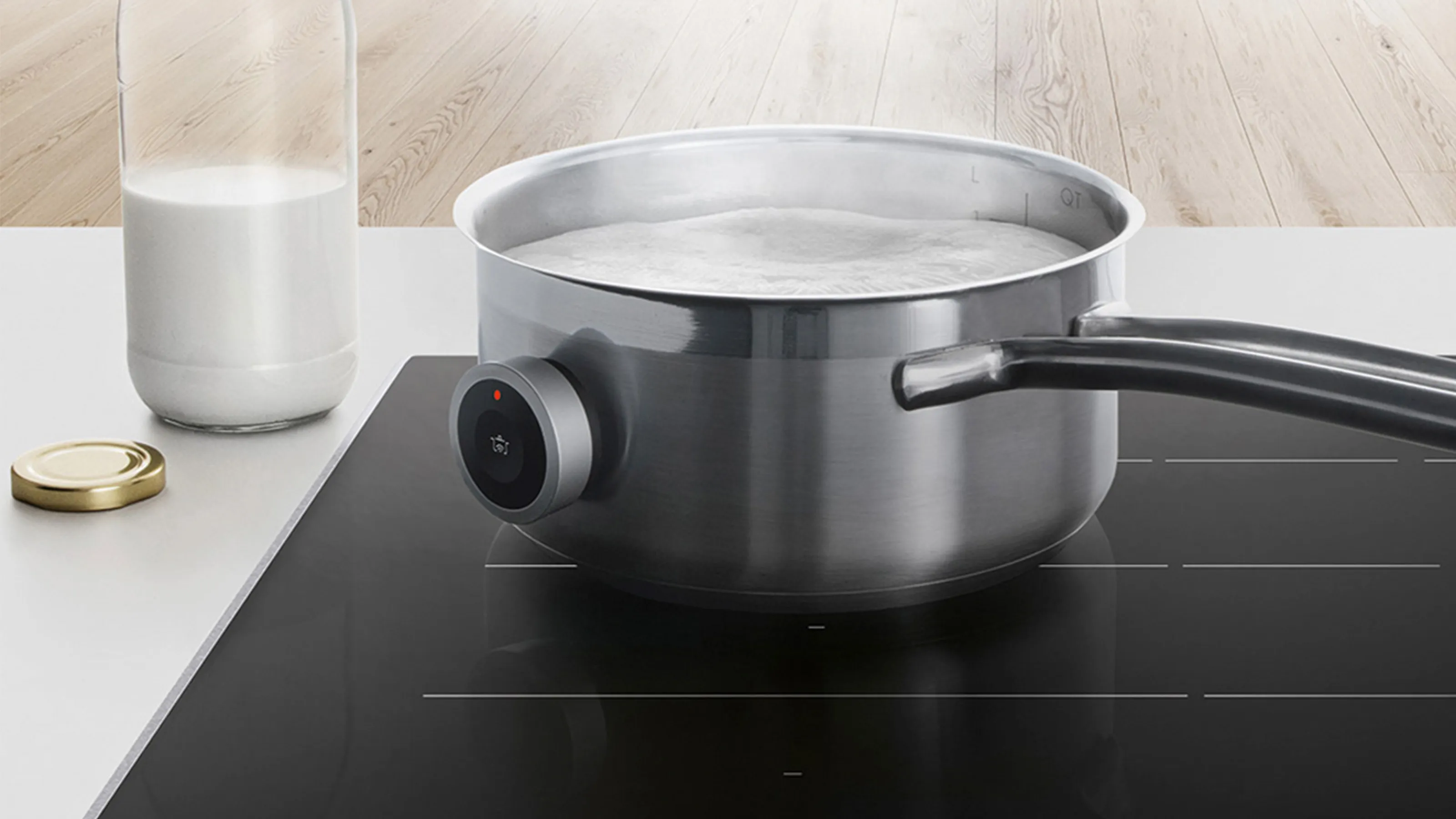 A hob with a pot of boiling milk and a jug of milk next to it.