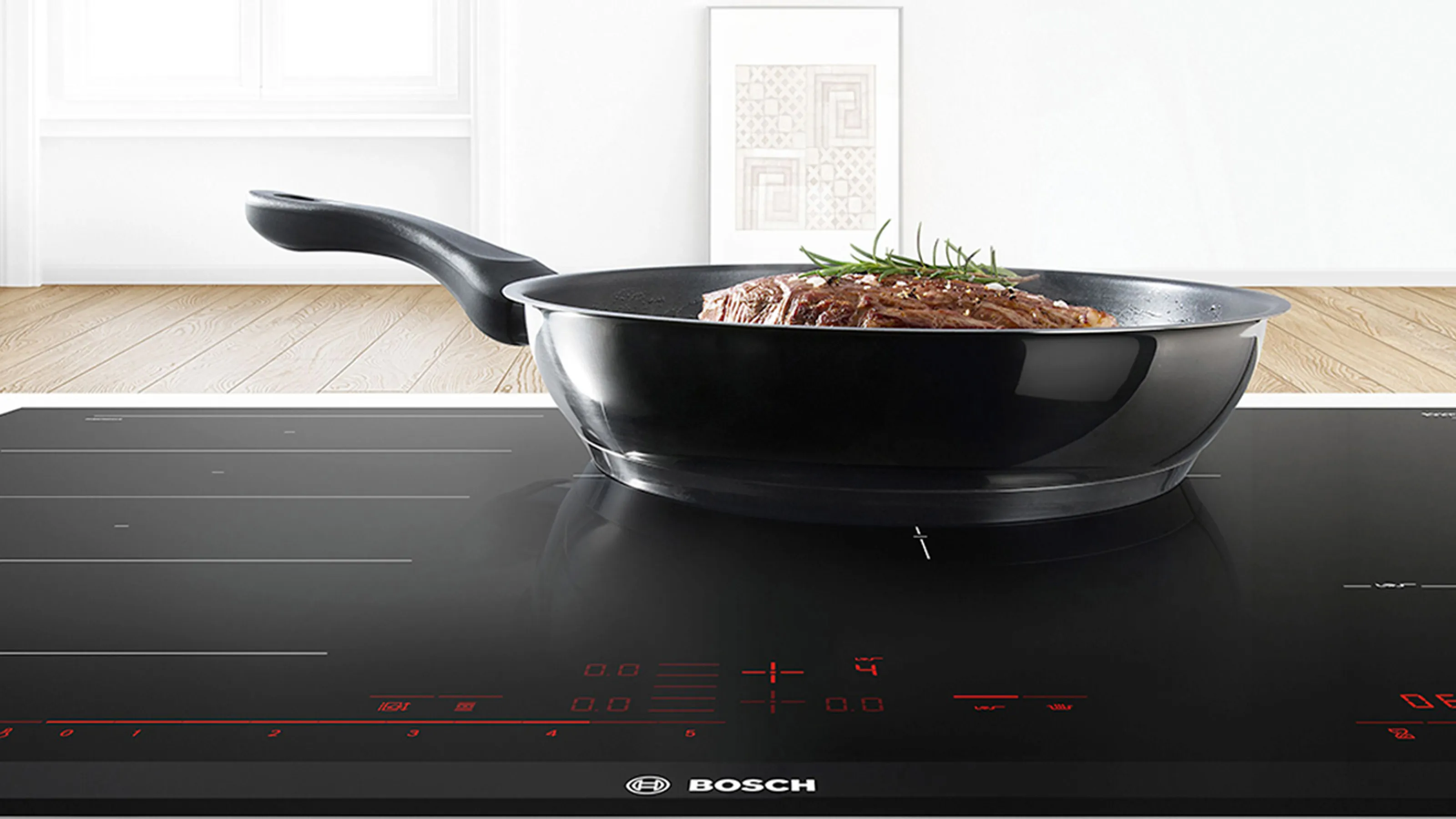 Cast iron pan and wok on a black stovetop against a white wall background.