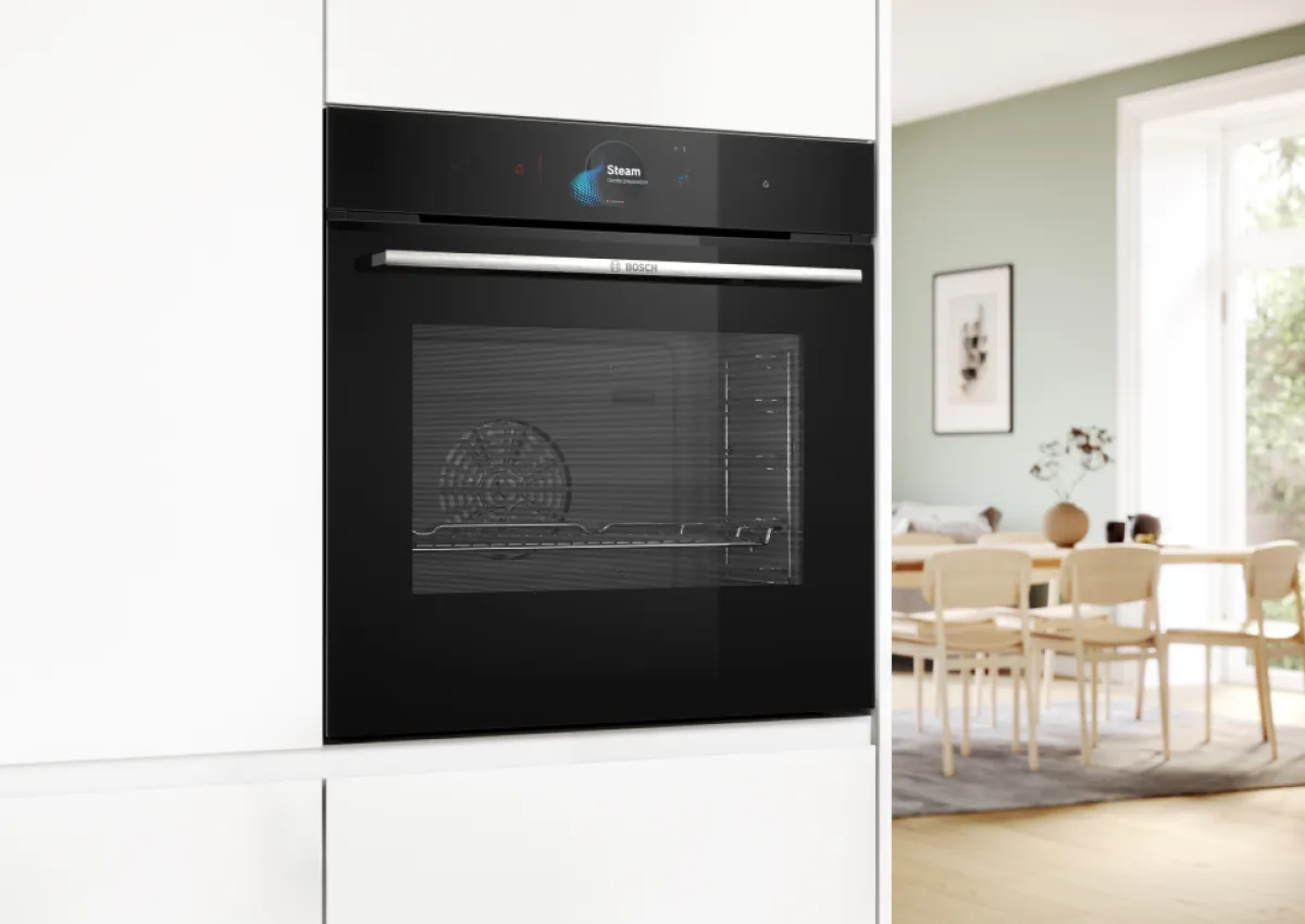 Horno negro incorporado en cocina moderna con comedor visible en fondo.