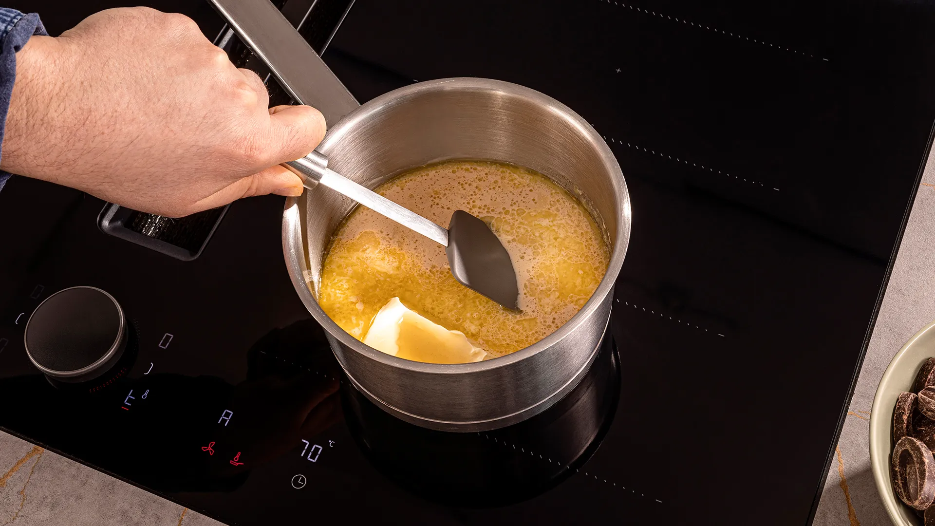 Cooking on stove, hand stirring pot with liquid, kitchen appliance, cooking utensil, food preparation.