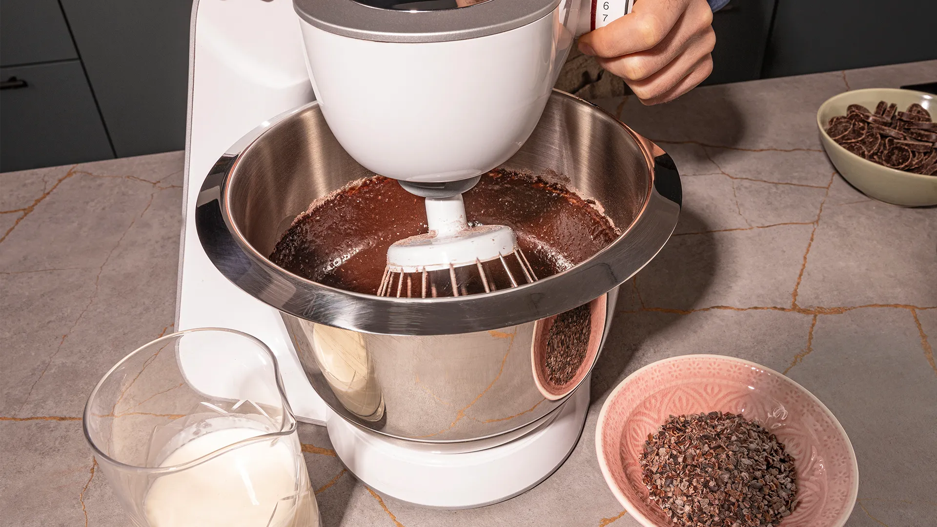 Mixing bowl with chocolate, milk, and other ingredients on kitchen counter.