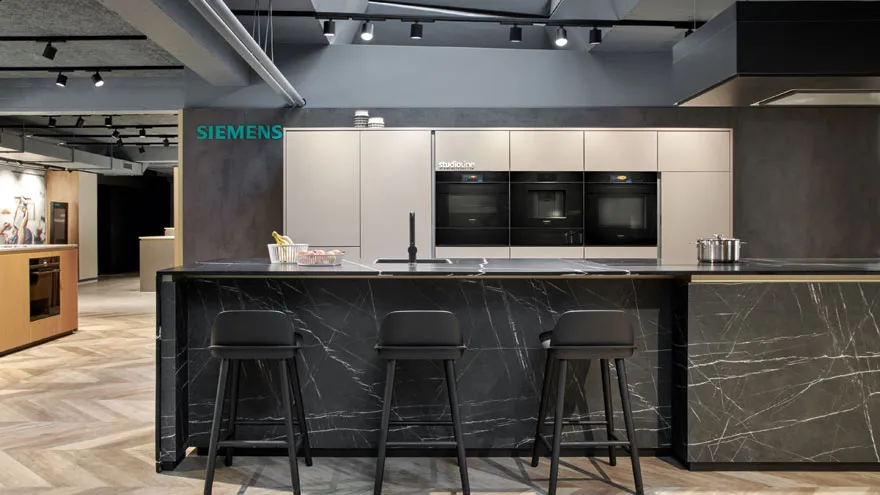 Moderne Küche Showroom mit schwarzem Marmor Arbeitsplatte, Barhocker und Siemens-Geräte.