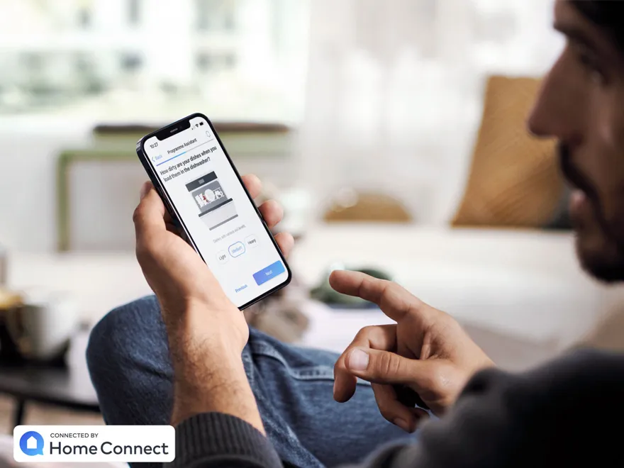 Eine Person bedient den Geschirrspüler-Programm-Assistenten über die Home Connect App auf ihrem Smartphone.