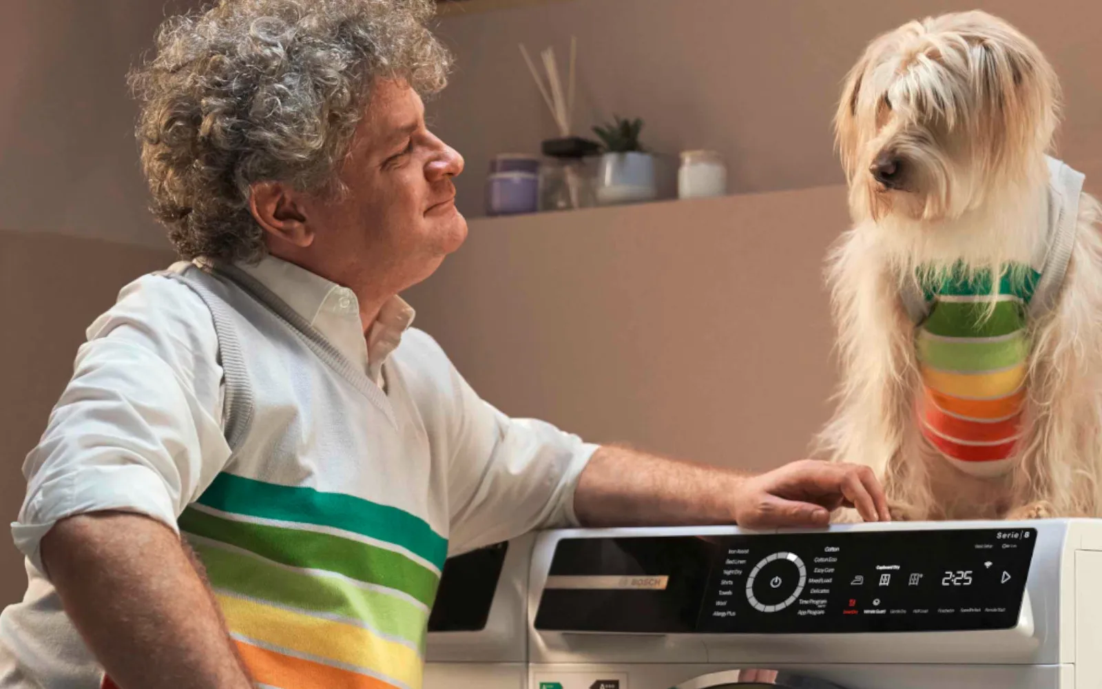 Man med hund som står vid tvättmaskin.