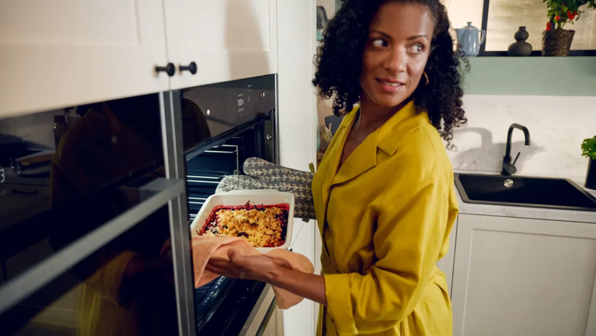 A woman loading an oven with a tray of food.