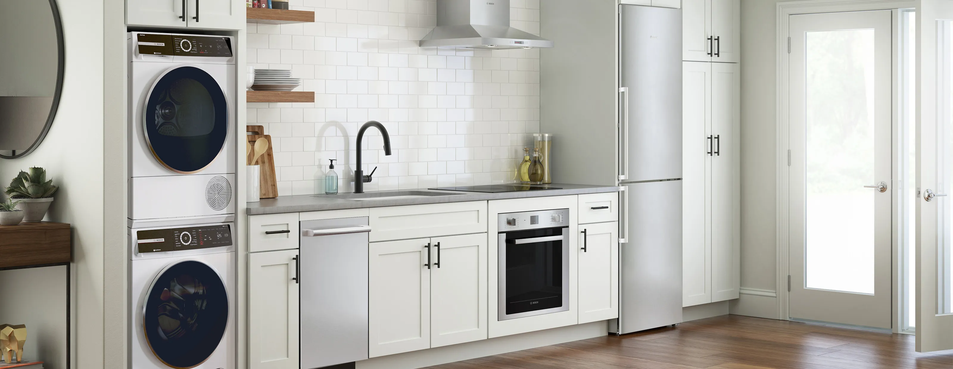 Modern small kitchen with Bosch stainless appliances such as washing and drying machines, dishwasher, stove top, oven and refrigerator