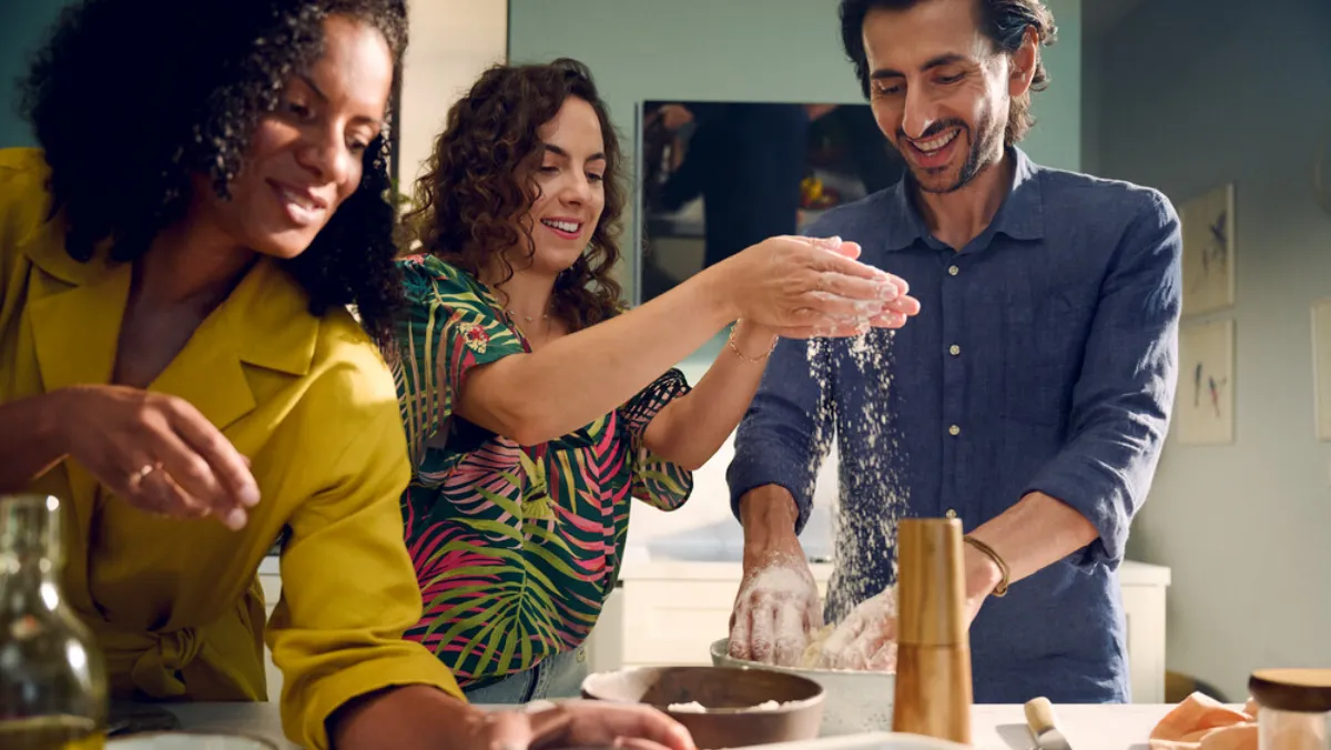 Group of three people cooking in a kitchen, working on a recipe.