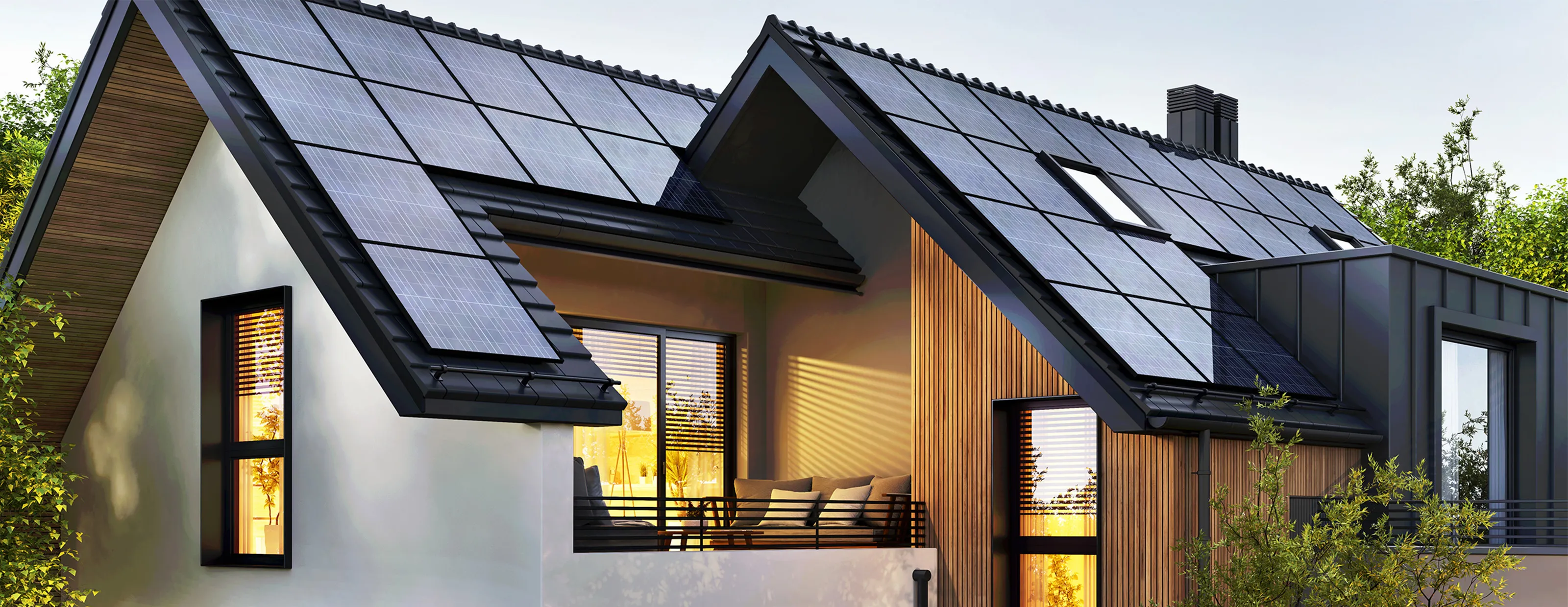 Modernes Wohnhaus mit einer großflächigen Solaranlage auf dem dunklen Satteldach und einer Fassade aus Holz und weißem Putz.