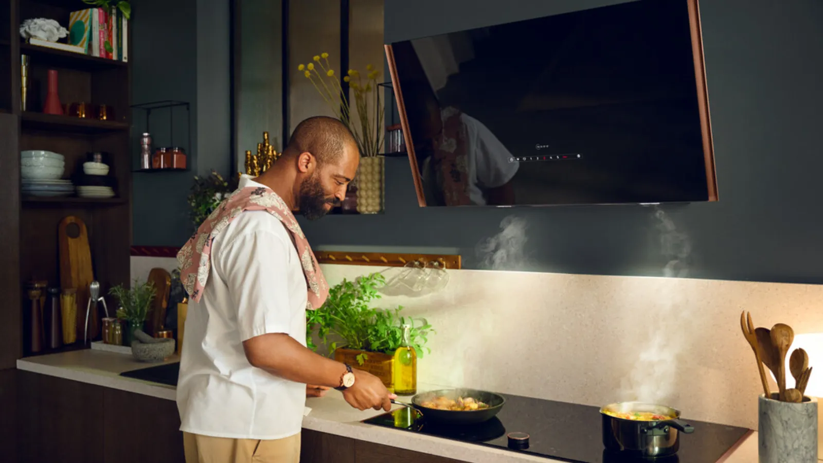 A man cooking on a stove top in a kitchen, stirring a pot with steam rising.
