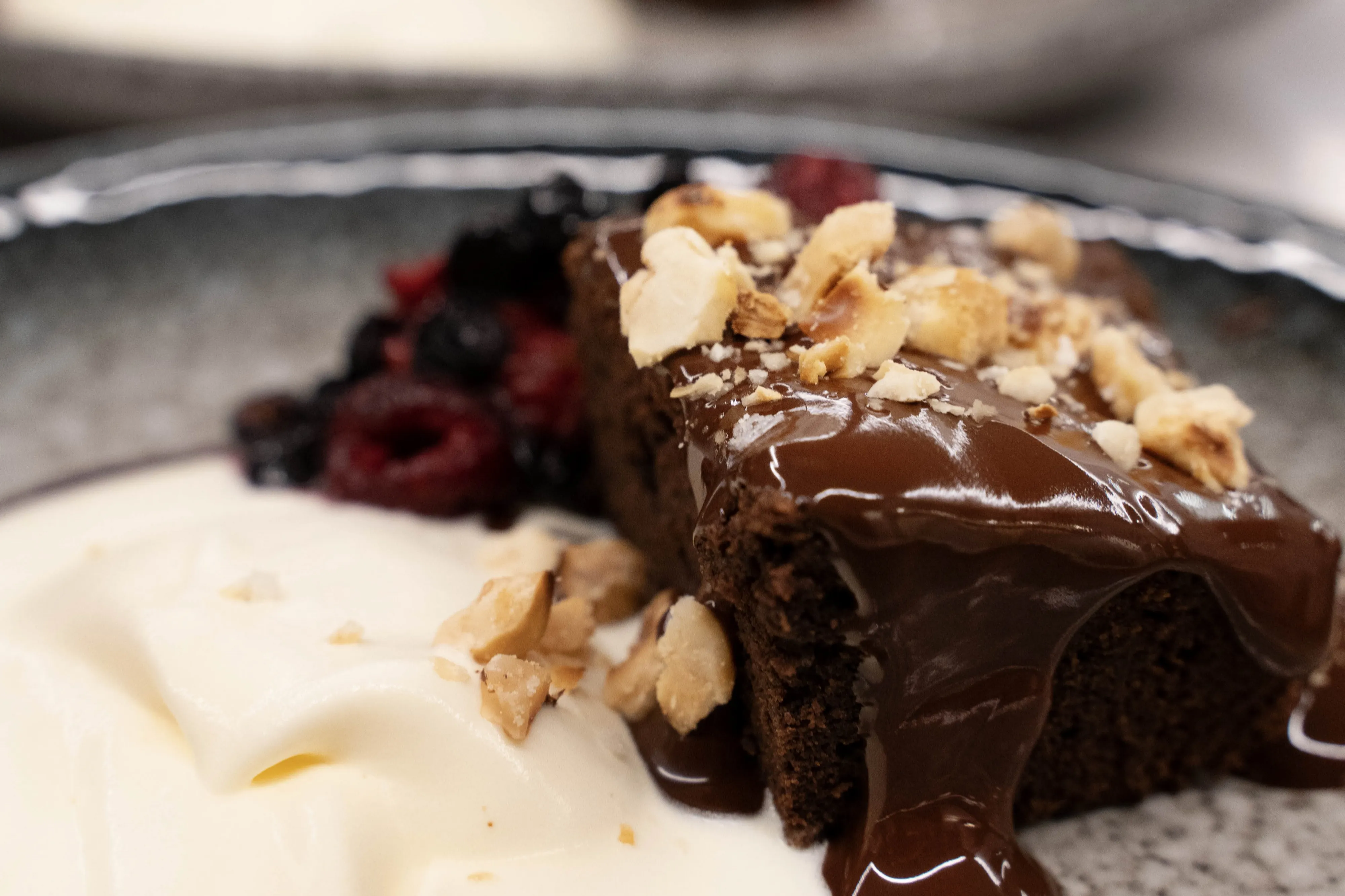 Decadent chokladkaka med en rik glasyr, toppad med huggna nötter, serveras på en tallrik.