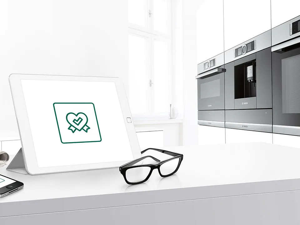 Nowoczesne urządzenia kuchenne, tablet z ikoną serca, okulary na liczniku, minimalistyczny design.