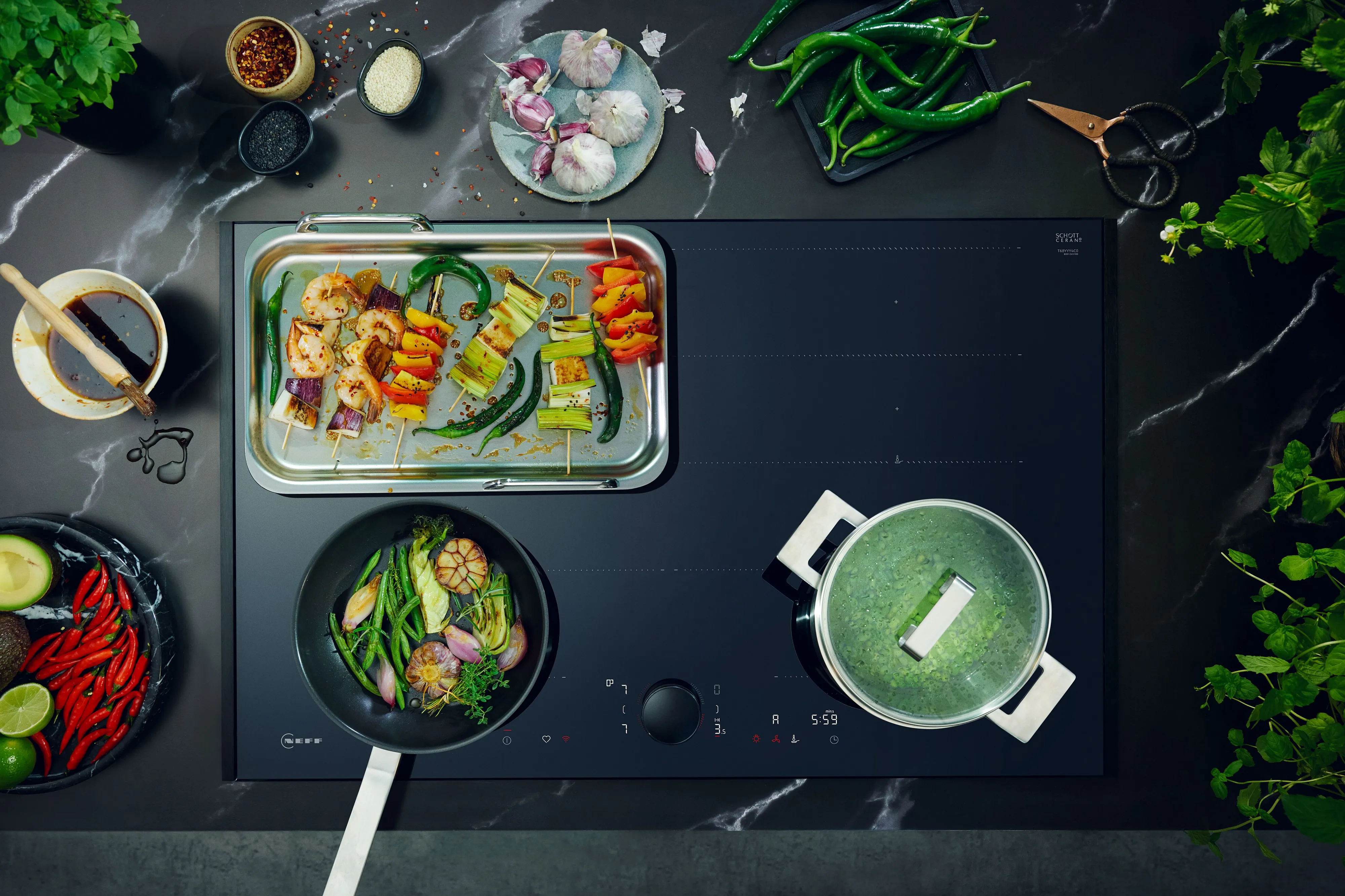Vista dall'alto di un moderno piano cottura con spiedini di verdure alla griglia, verdure saltate in padella e una pentola con il coperchio, circondati da ingredienti freschi e spezie.