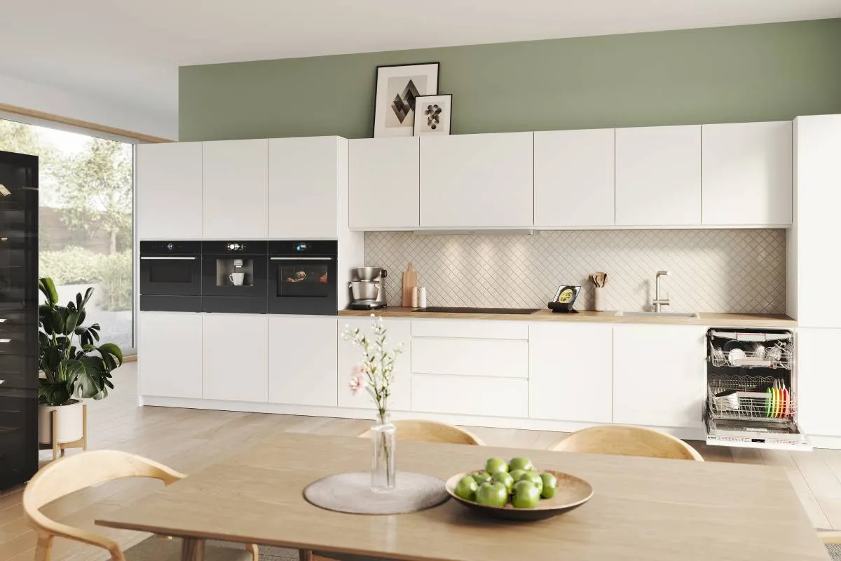 View of kitchen with Bosch appliances, white counters, and light green walls.