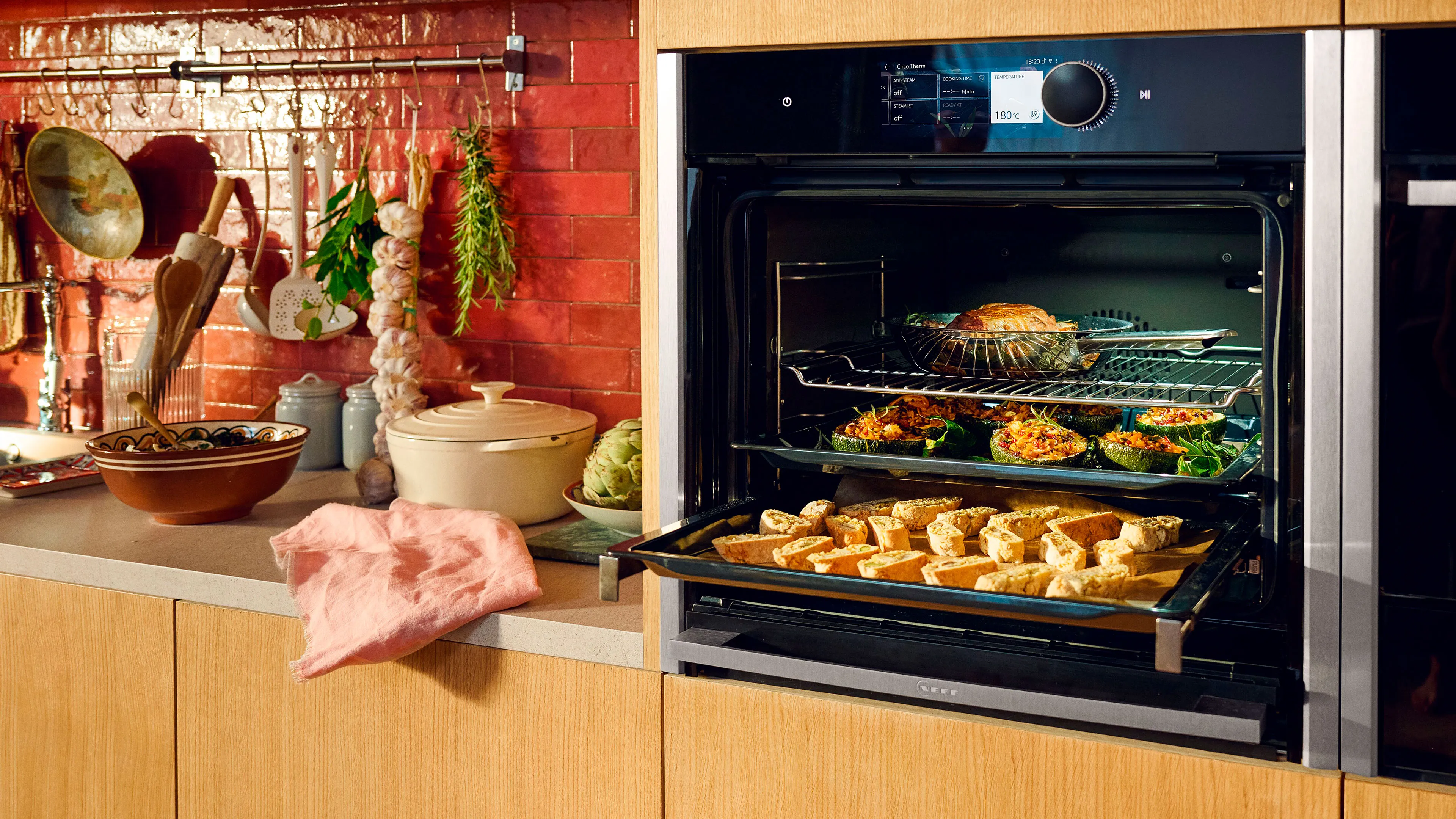 A kitchen featuring a stove and oven, both in use, with delicious food being prepared inside the oven. 
