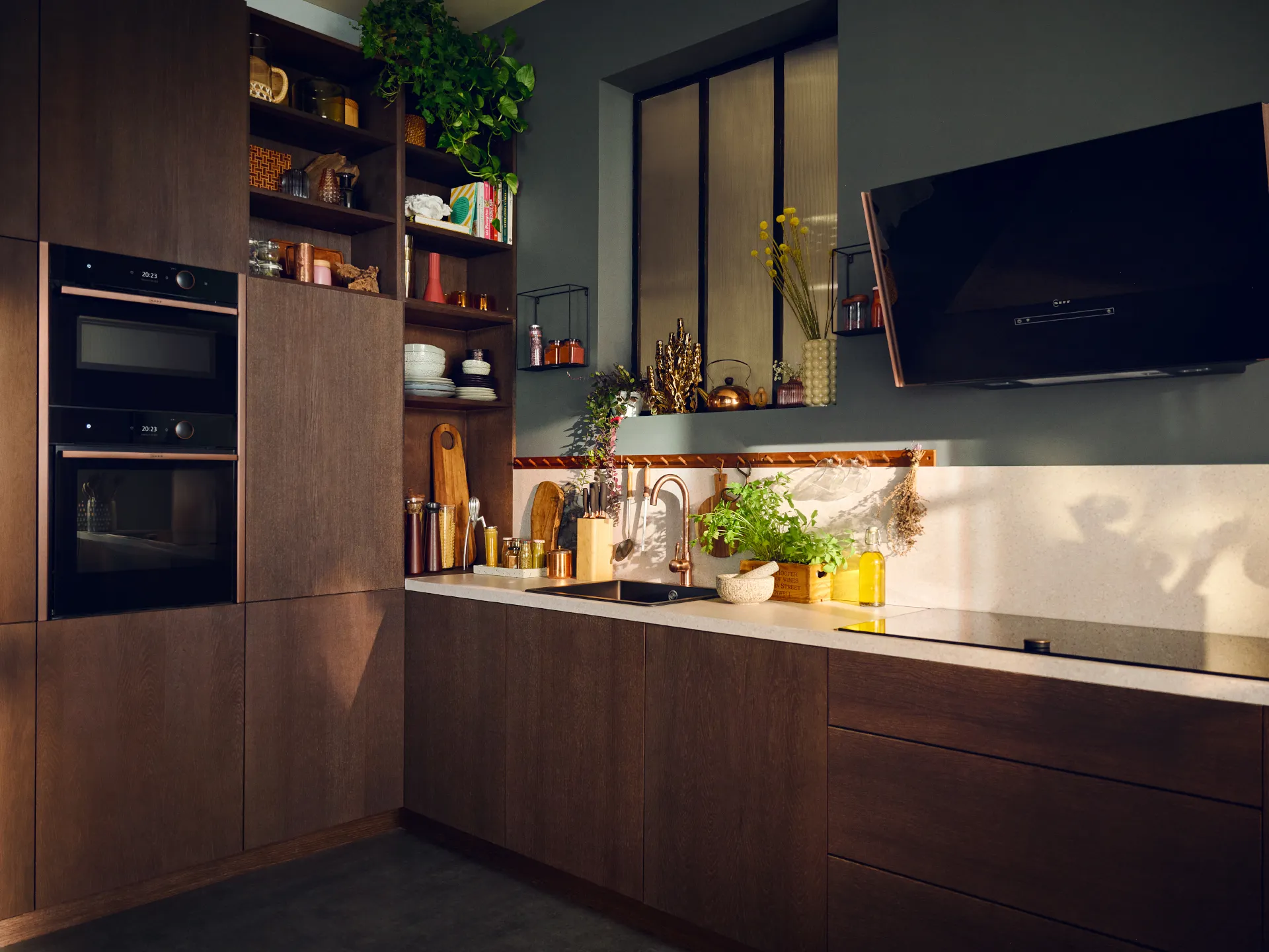 Modern kitchen with dark cabinets, open shelves, plants, and appliances.