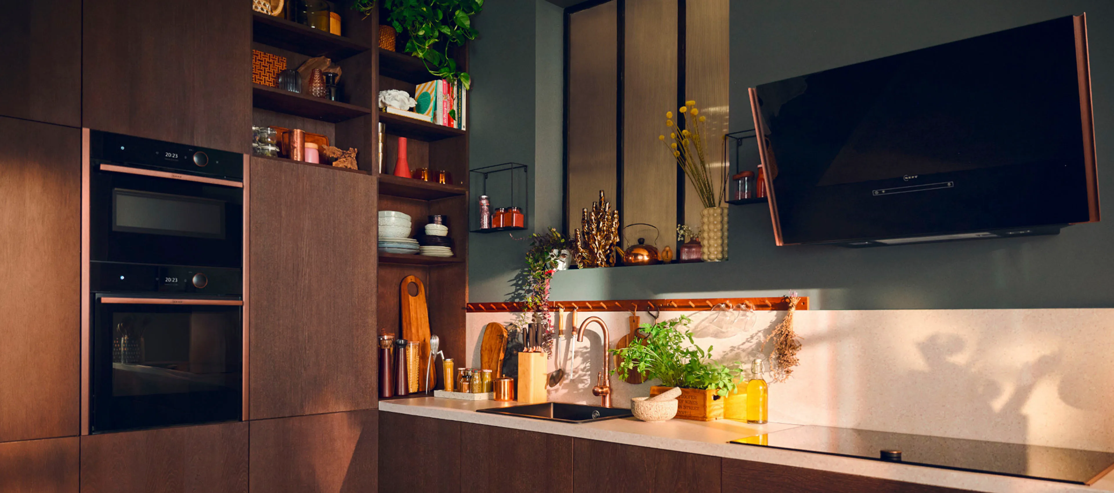 Μια κουζίνα με θερμά χρώματα και ξύλο, όπου διαθέτει οικιακές συσκευές NEFF.