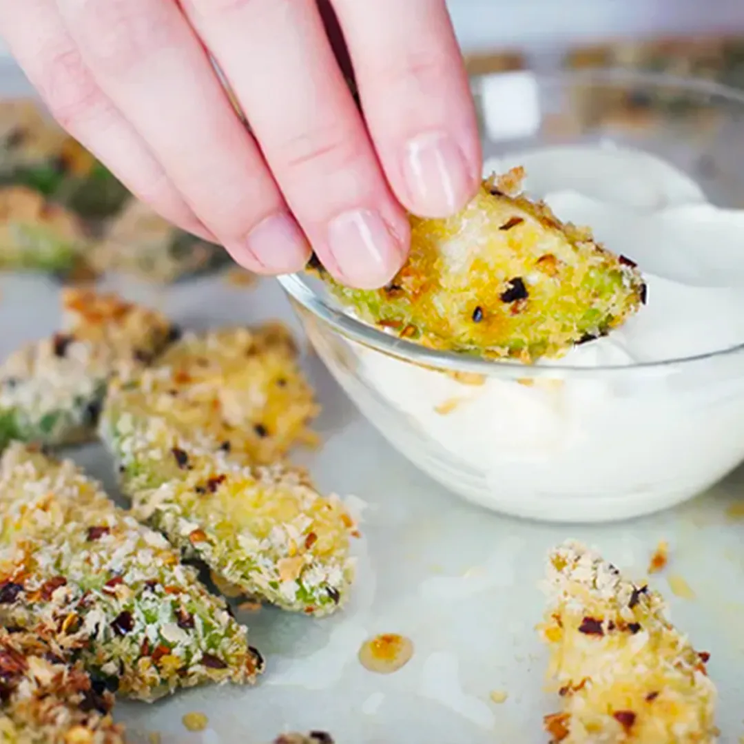 Dipping finished avocado fries in sauce