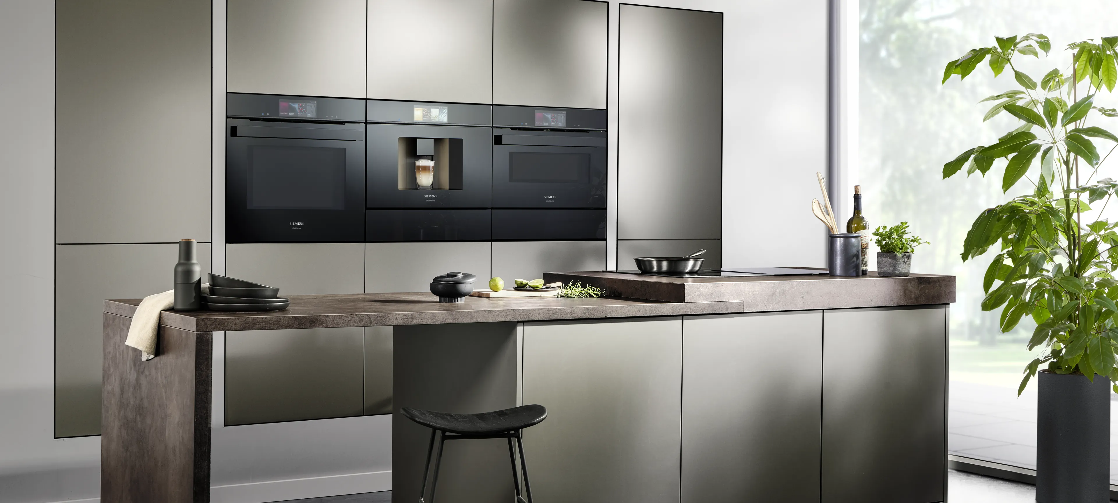 Modern kitchen with sleek black appliances, dark cabinetry, and a wooden countertop.
