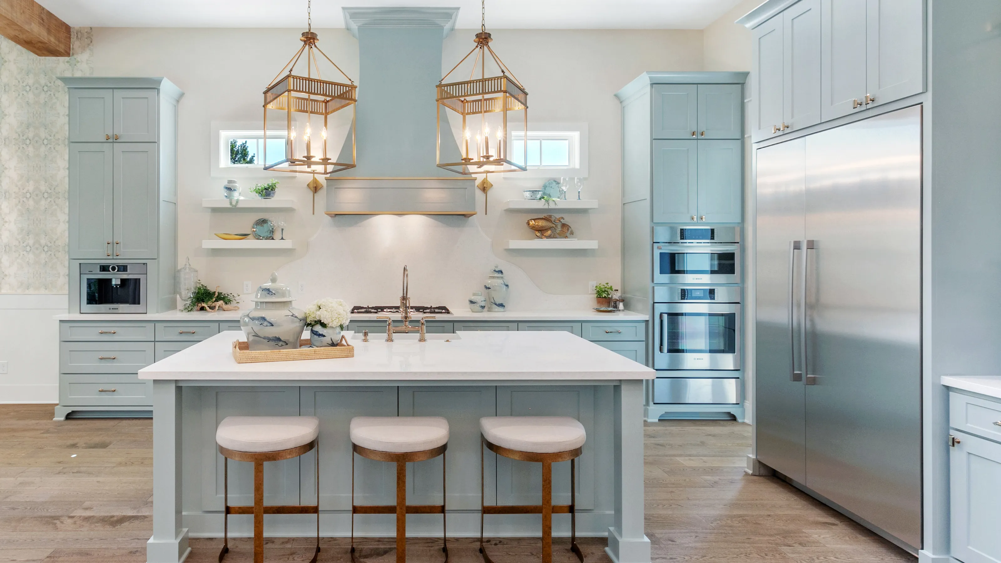 Modern kitchen with light blue cabinets, island, and Bosch stainless steel appliances.