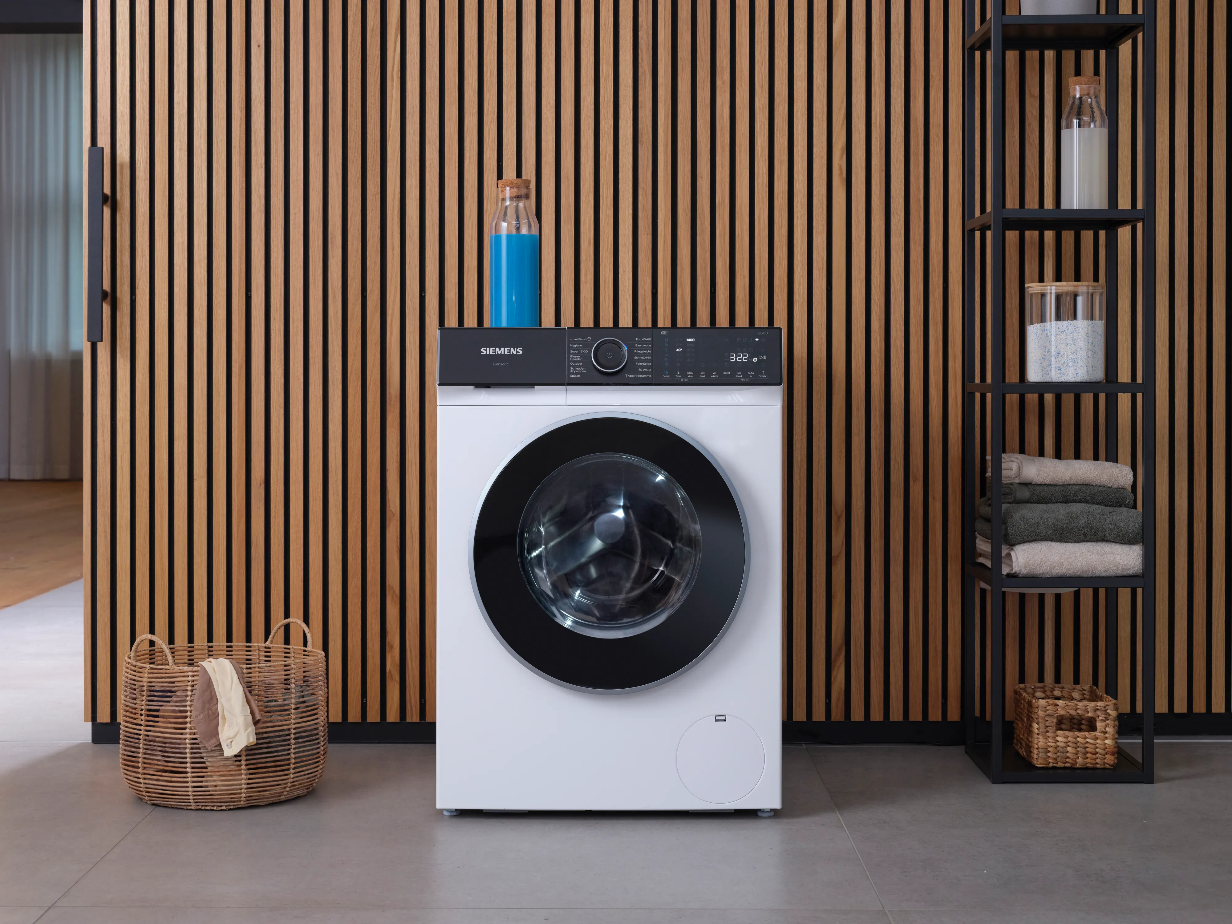 Eine moderne Siemens-Waschmaschine steht in einem stilvollen Raum mit Holzvertäfelung, einem geflochtenen Korb und ordentlich gestapelten Handtüchern