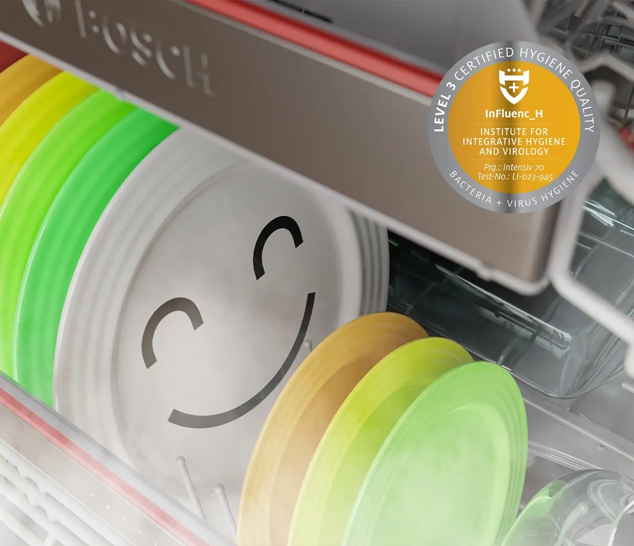 Dishwasher with colorful plates and a smiling metal plate, hygiene certification seal.