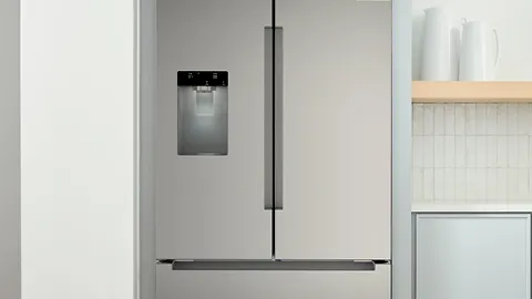 Modern Bosch stainless steel refrigerator with water dispenser in a minimalist kitchen.