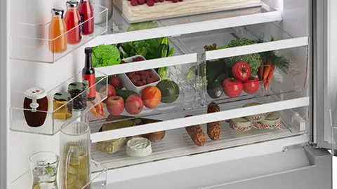 Open Bosch refrigerator filled with fresh produce, drinks, and other food items.