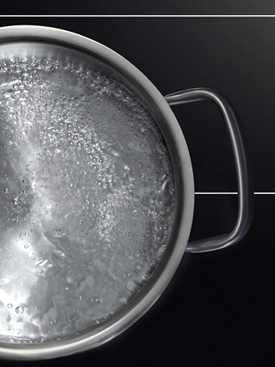 Boiling water in a transparent pot, steam and bubbles visible, against a dark background.