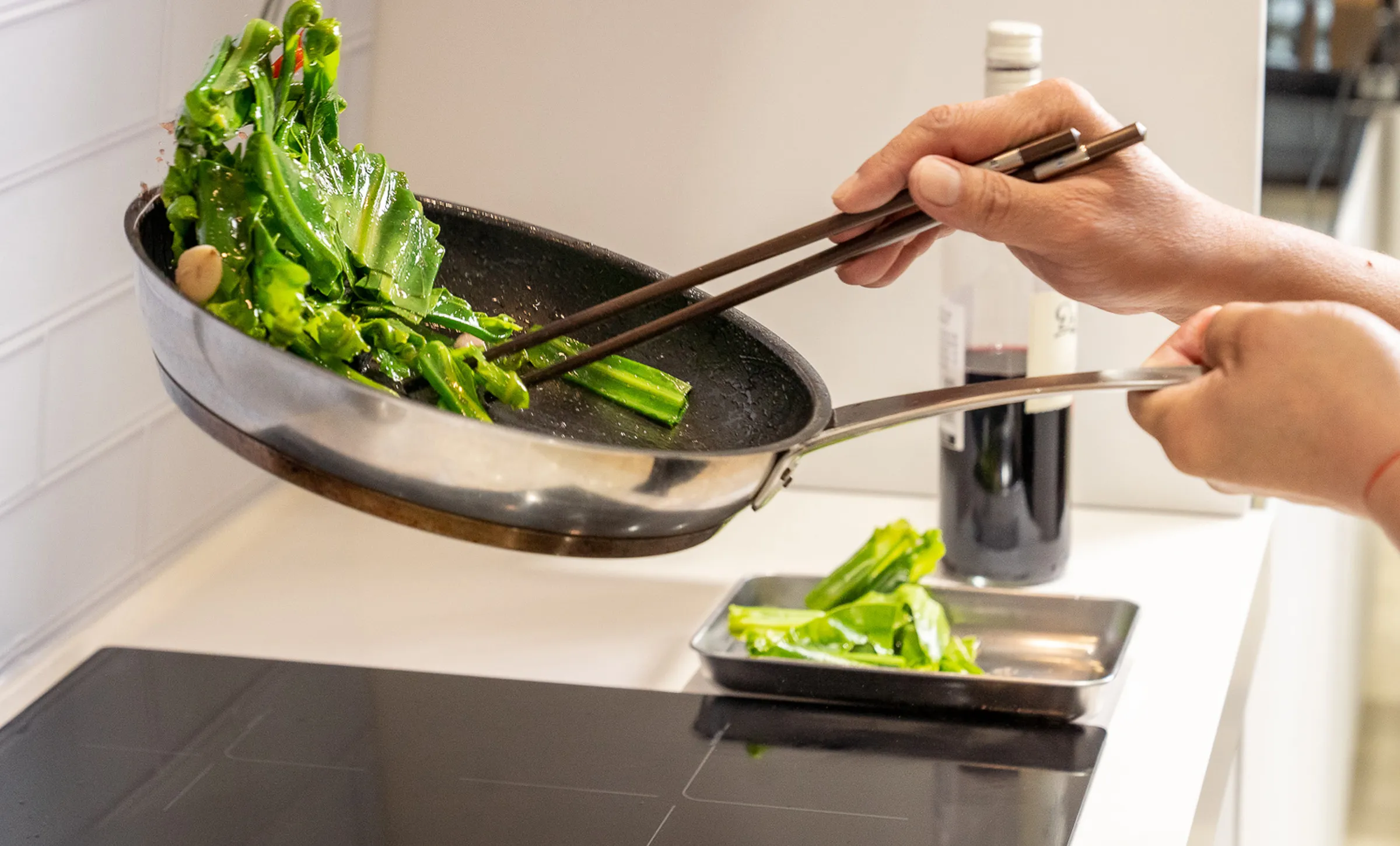 Person cooking green veg in a pan