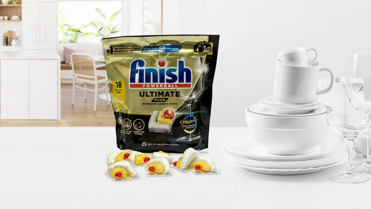 An open package of dishwasher tablets on its side with tablets tumbling out onto the worktop.