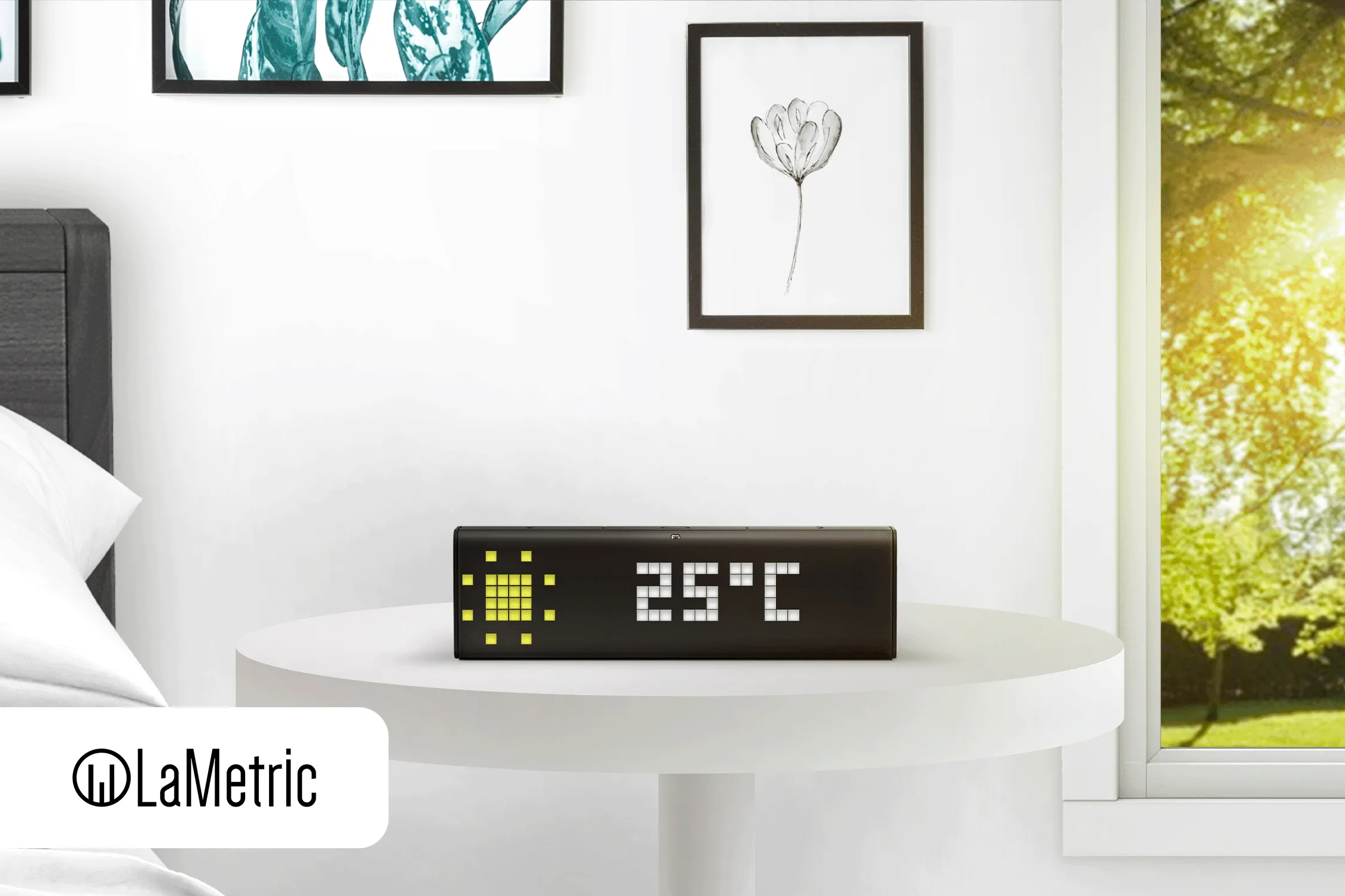 Smart clock on a bedside table displaying 25°C and sun symbol, with a window and wall art.