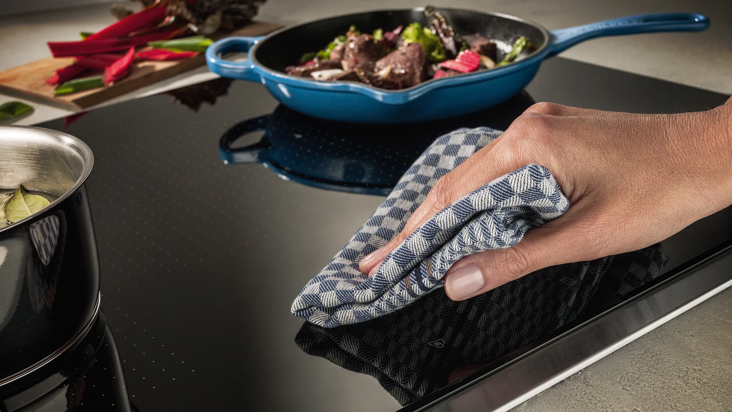 Person wiping an induction hob with a cloth.