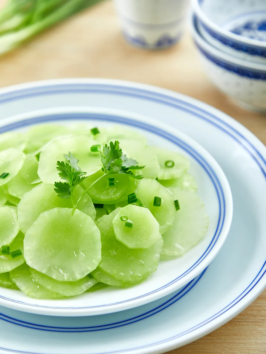 Bord met gesneden uien en sla in olie op een wit bord.