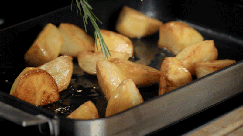 Cooked potatoes being shaken on oven dish