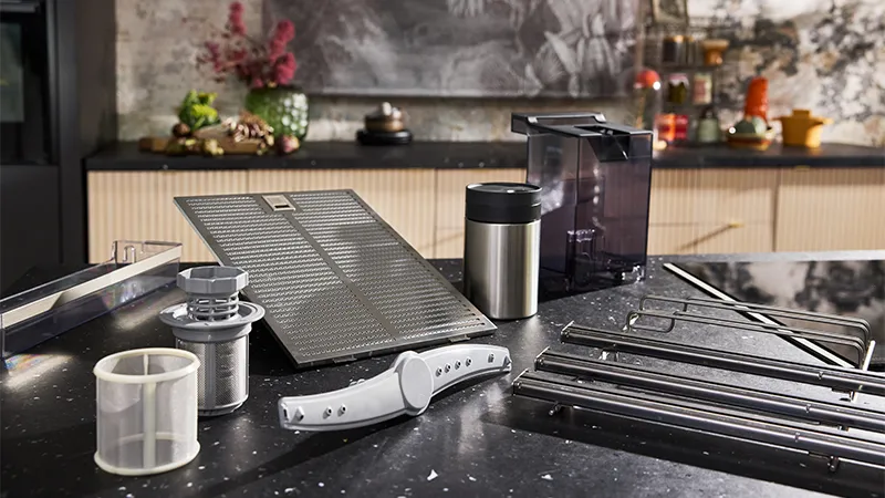 alt-A collection of kitchen appliance components, including filters, containers, and metal rods, arranged on a countertop.