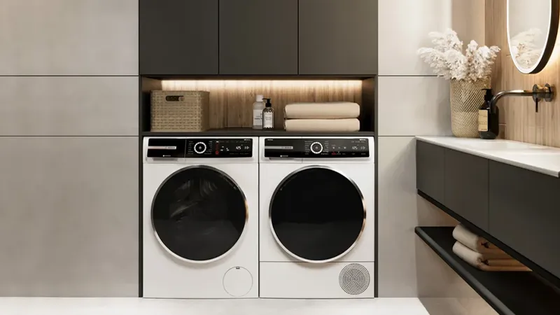 White Bosch washing and drying machine side by side under black cabinets