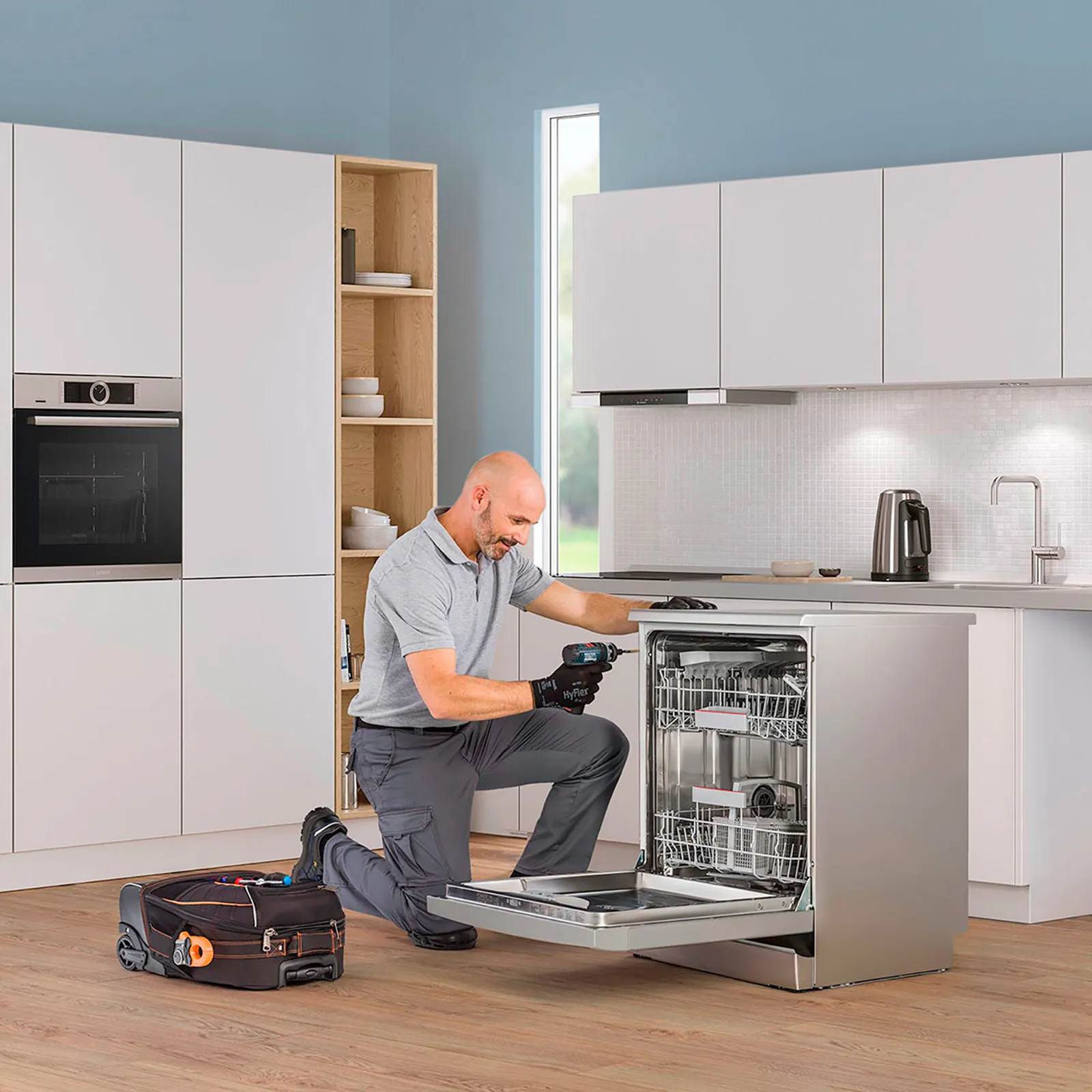 alt-Technician repairing a Bosch oven in the kitchen and white kitchen in the background.