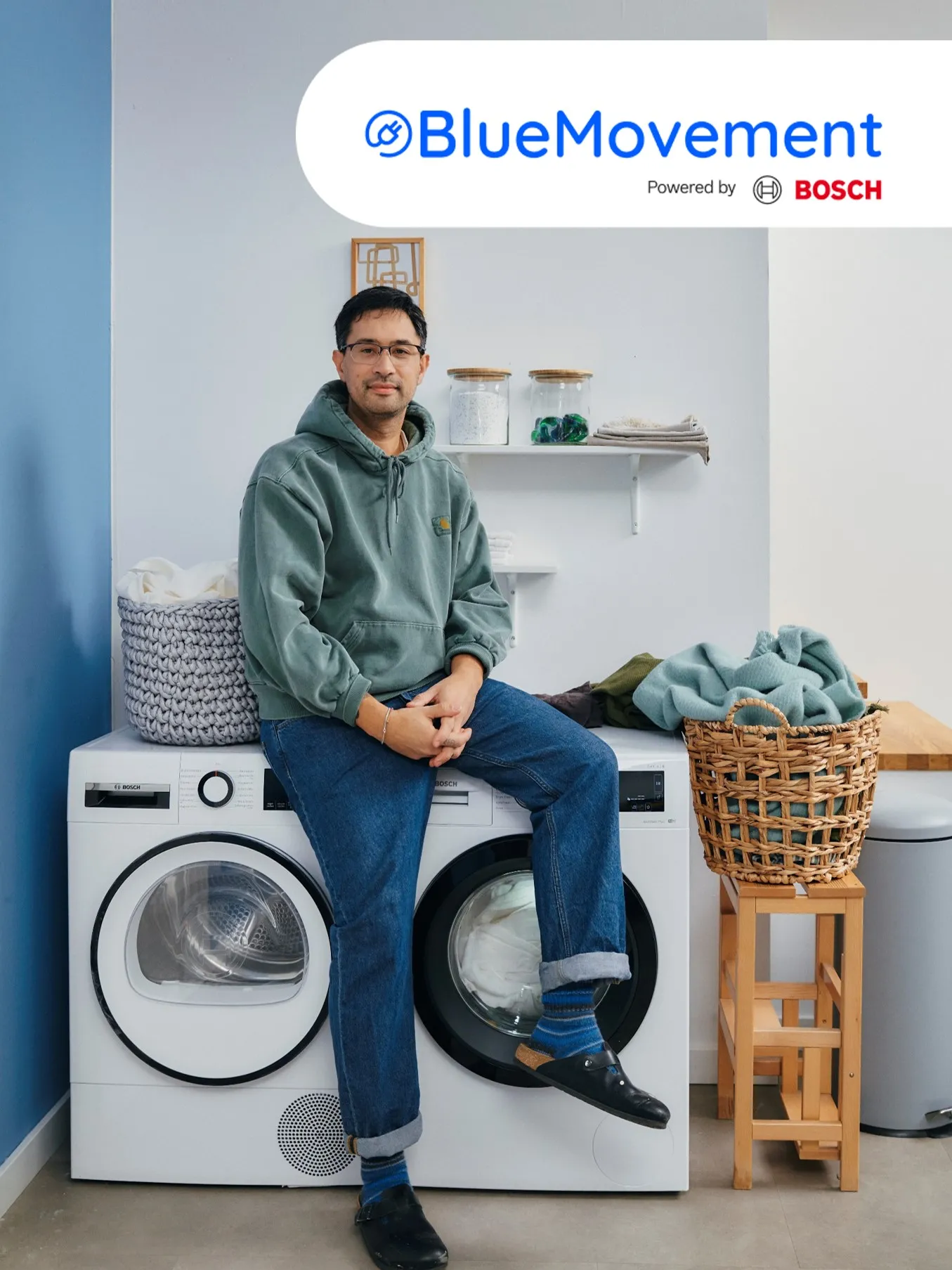 Man zittend op wasmachine in wasruimte met Blue Movement by Bosch branding.