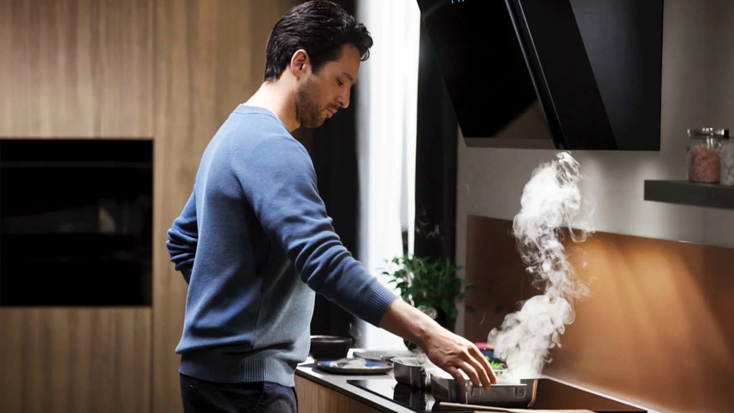 A man is cooking in a kitchen, with steam rising from the stove, creating a warm and inviting atmosphere.