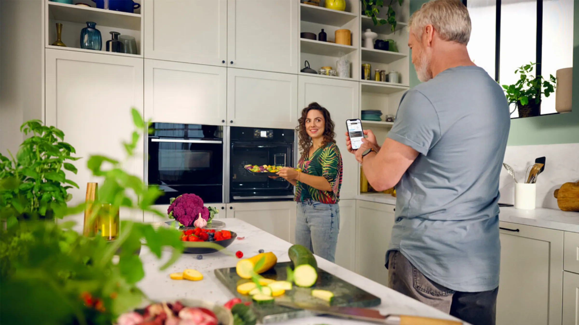 Couple in kitchen using home connect app to assist cooking