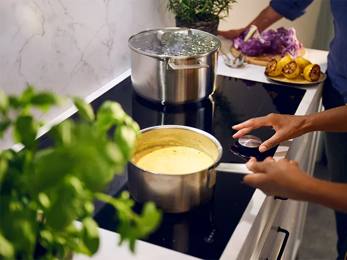 Cooking on stove, boiling liquid, fresh herbs, kitchen counter, cooking utensils, hands preparing food.