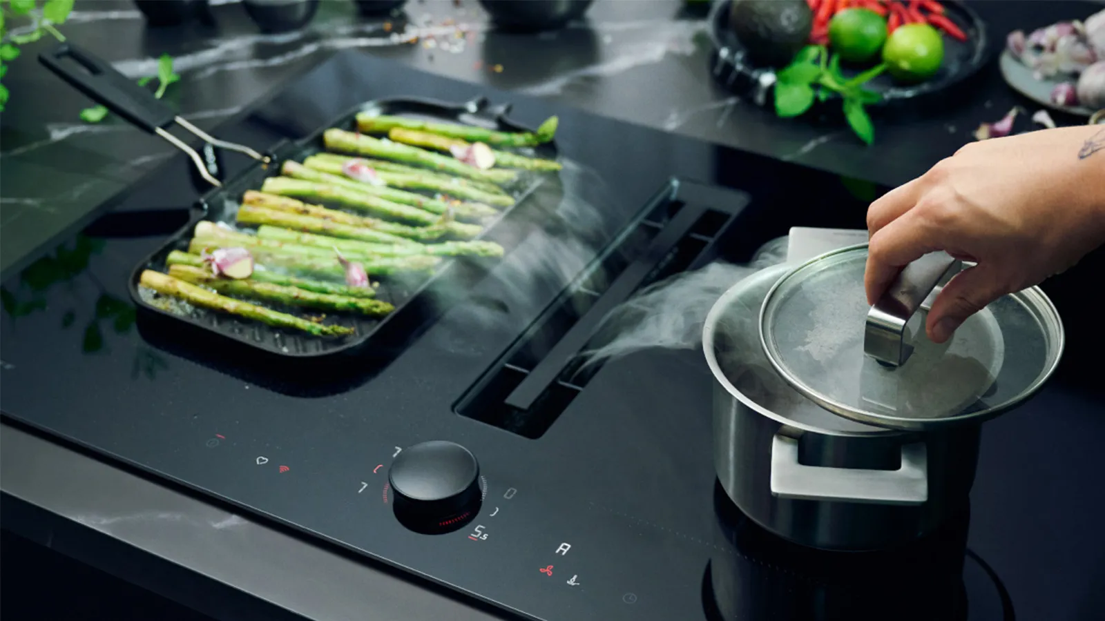 Cooking asparagus on a stovetop with a pot and utensils in the background.