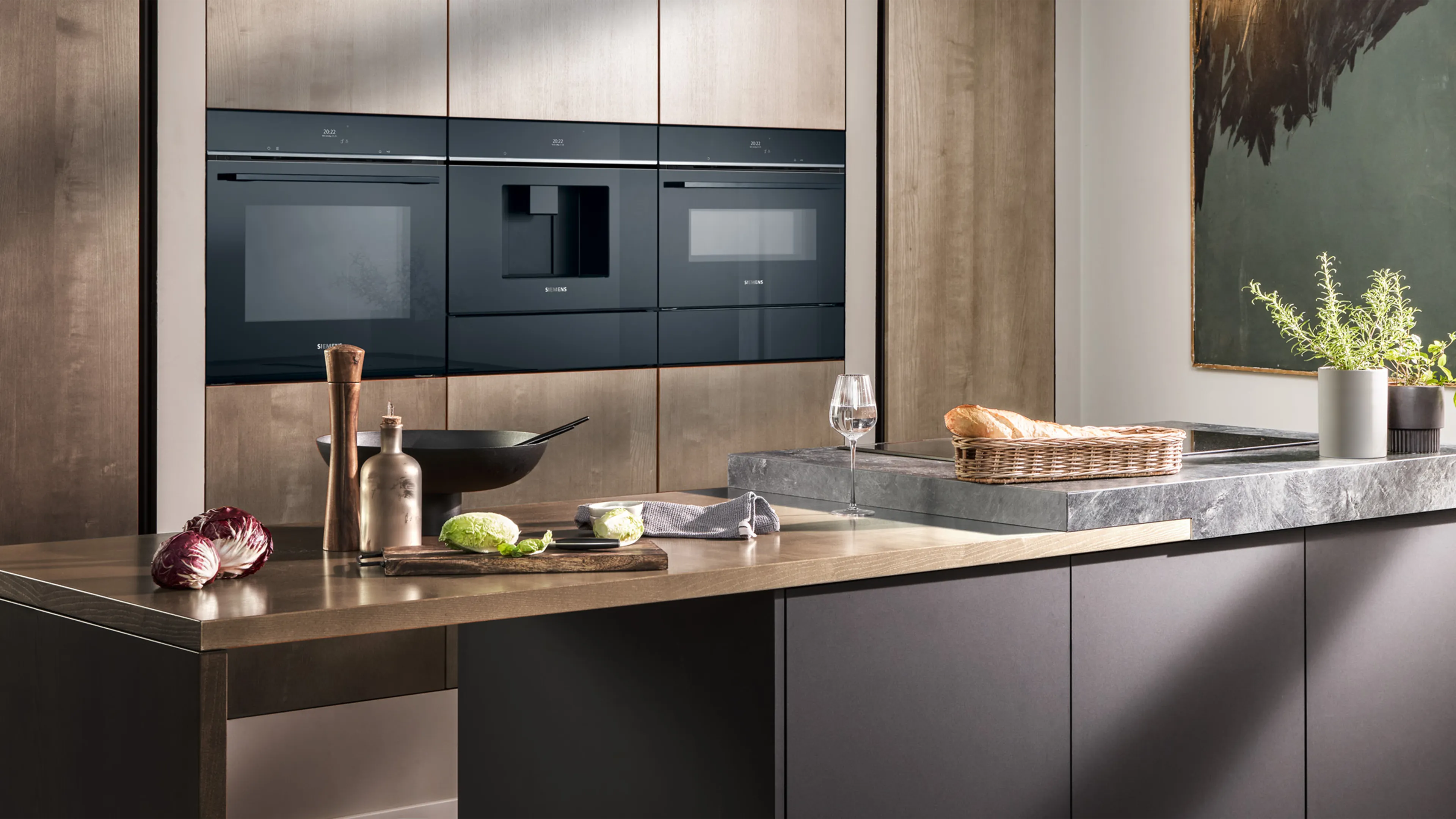 Cucina moderna con isola centrale, elettrodomestici da incasso Siemens neri e piante decorative