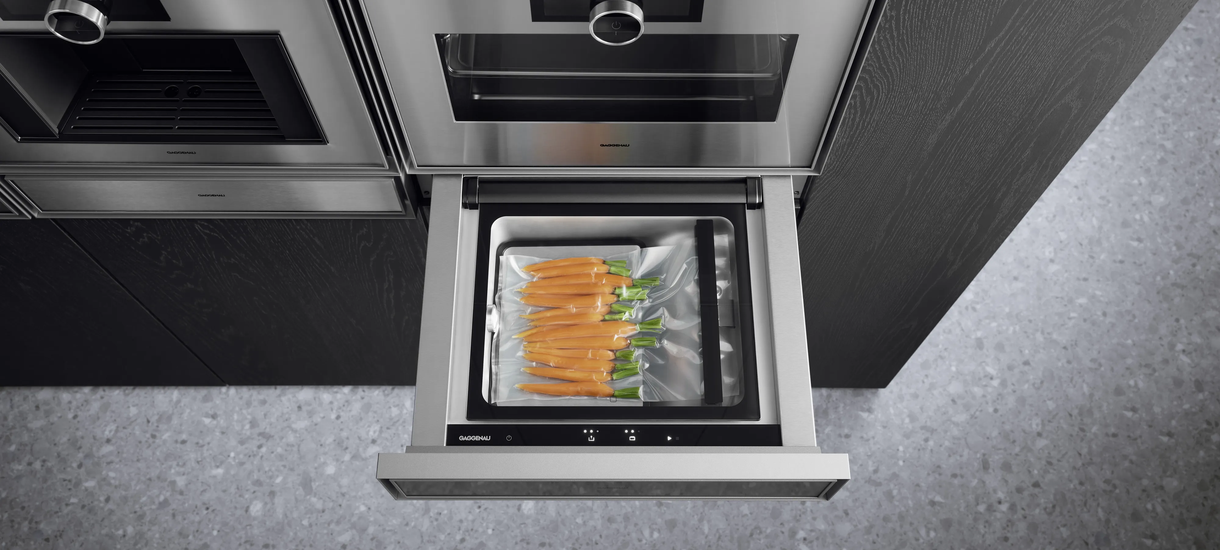 Plan view of an open Gaggenau Expressive series Vacuuming drawer in the process of sealing carrots