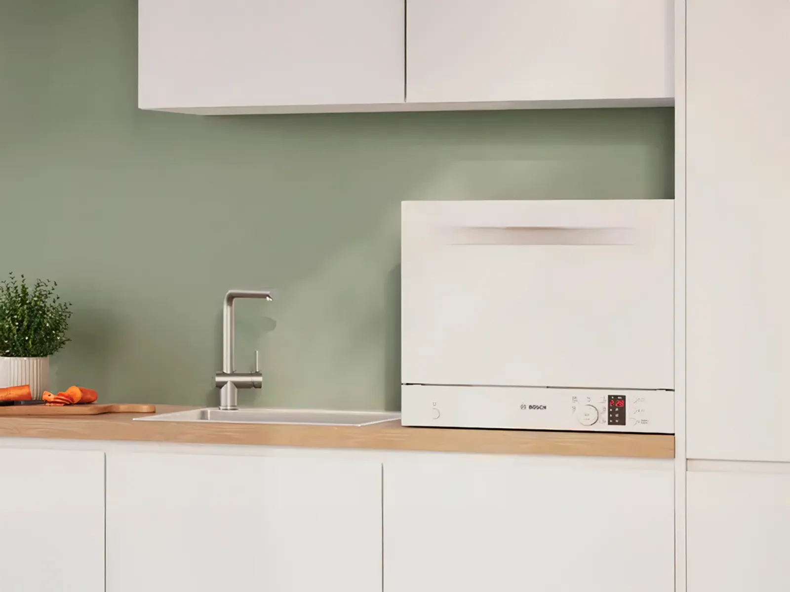 Vit kompakt fristående diskmaskin placerad nära diskbänken.