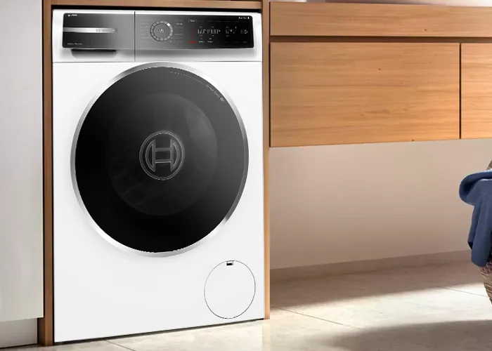 Modern mutfak ayarında dairesel cam kapı ve kontrol paneli ile çamaşır makinesi.